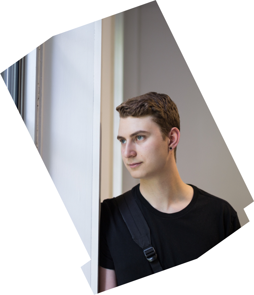 Aidan Messom, an Industrial Engineering student at Ryerson University, sits in a hallway within the George Vari Engineering and Computing Centre building.