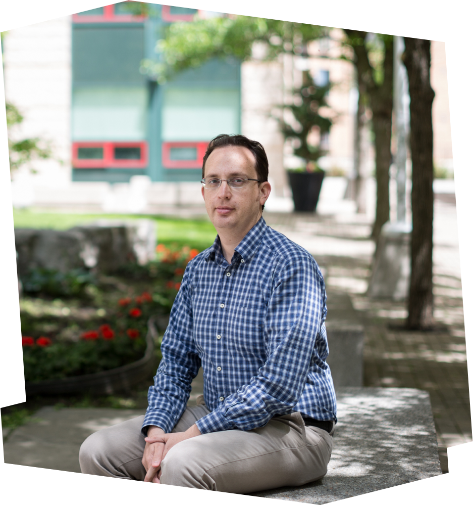 Can Kavaklioglu sits on a bench outside, on the Ryerson campus.